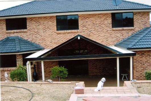 A brick house with a blue roof and a porch — Hunter & Mid Coast Patios In Newcastle, NSW