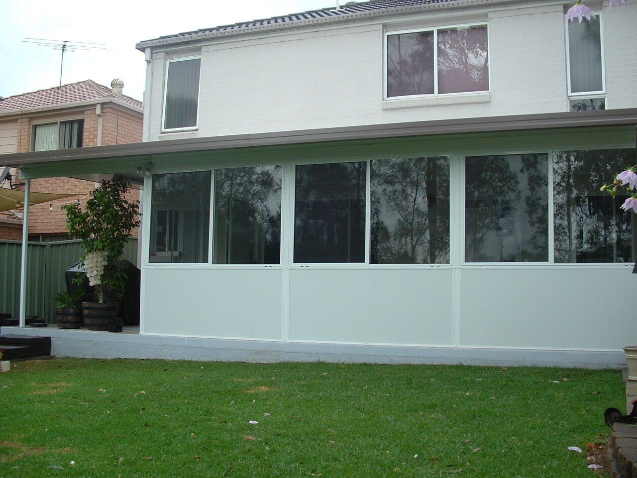 A white house with a covered porch and lots of windows — Hunter & Mid Coast Patios In Newcastle, NSW