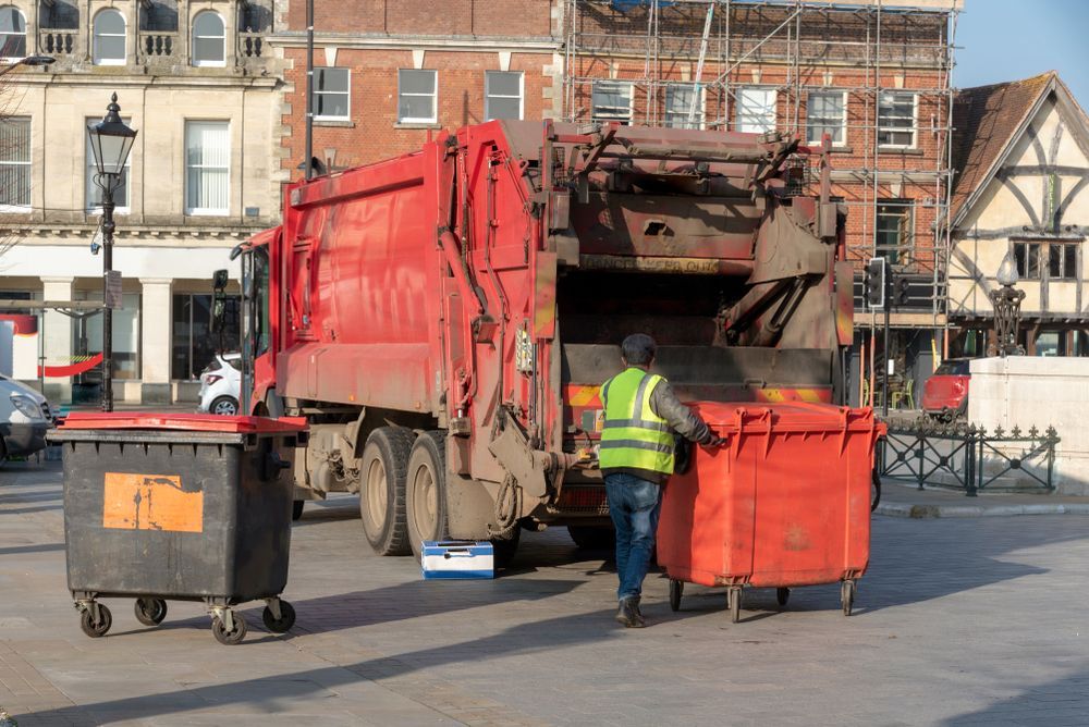 A Man is Loading Garbage Into a Garbage Truck — Gardners Yamba Skip Bin Hire in Yamba, NSW