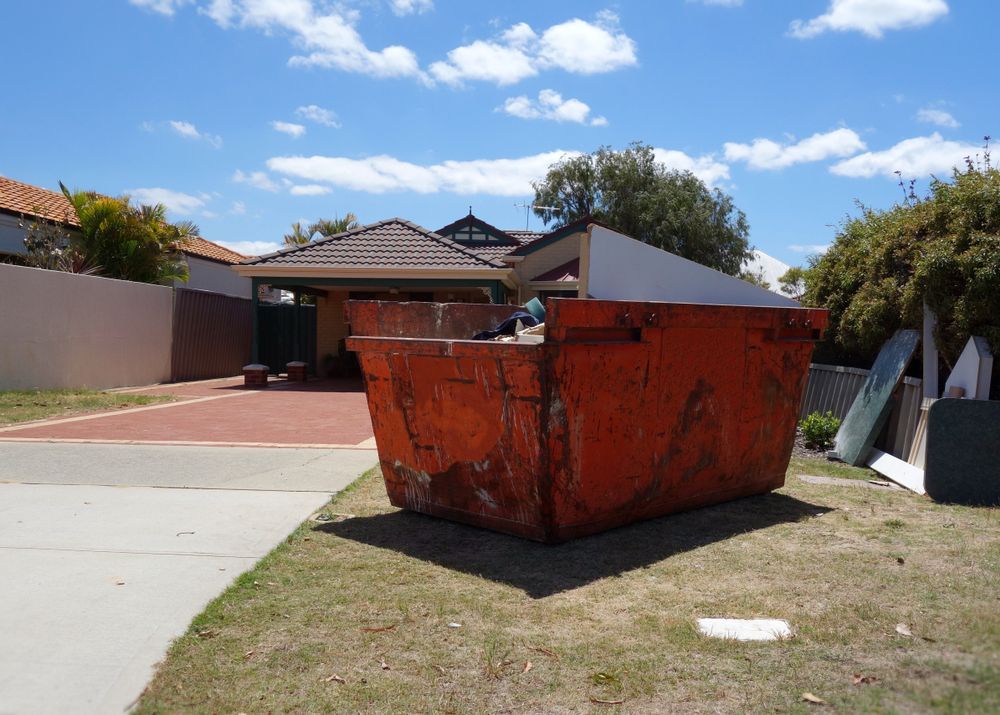 A Large Orange Dumpster is Sitting in Front of a House — Gardners Yamba Skip Bin Hire in Grafton, NSW