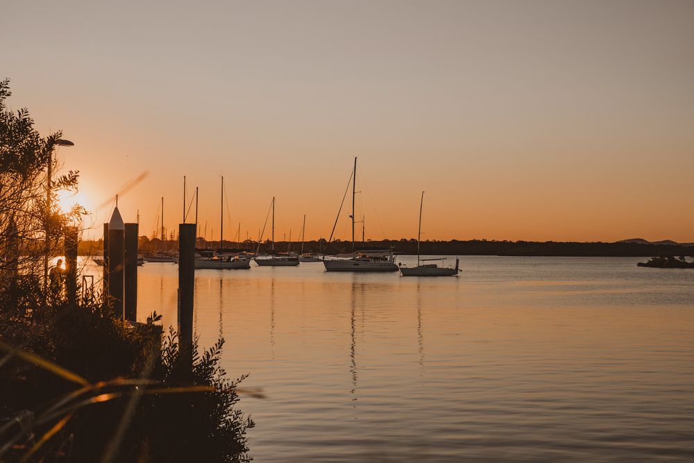 A Sunset Over a Body of Water With Boats Docked in the Water — Gardners Yamba Skip Bin Hire in Yamba, NSW