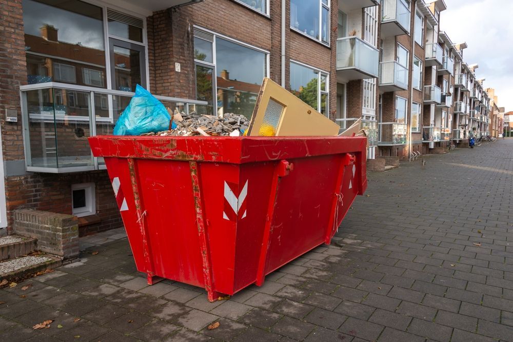 A Red Dumpster is Sitting on the Sidewalk in Front of a Building — Gardners Yamba Skip Bin Hire In South Grafton, NSW