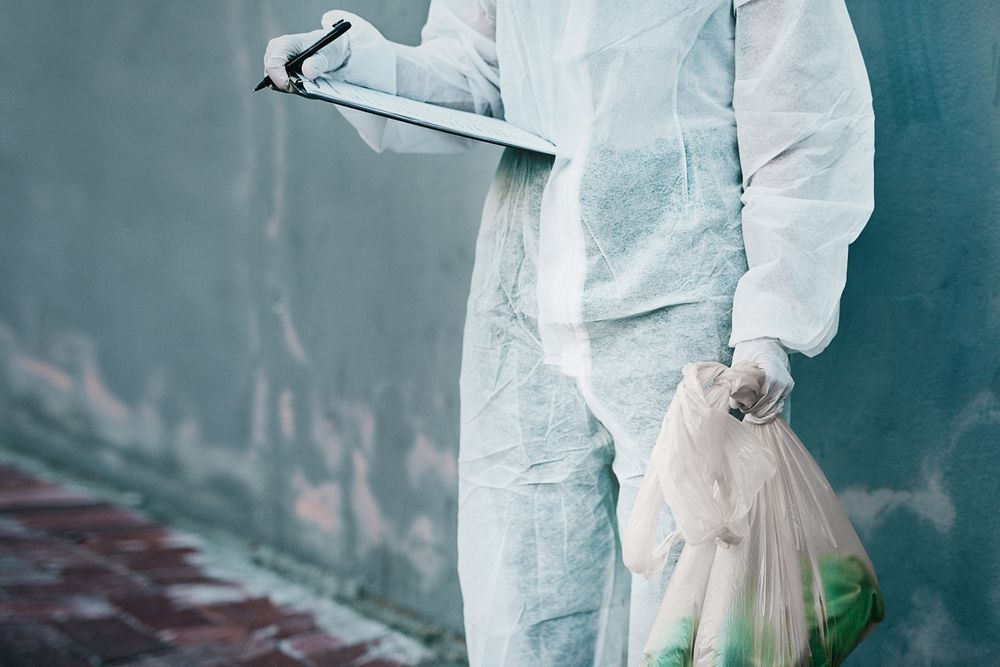 A Man in a Protective Suit is Holding a Trash Bag and a Clipboard — Gardners Yamba Skip Bin Hire in Grafton, NSW