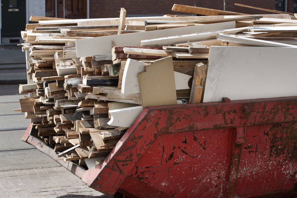 A Red Dumpster Filled With a Pile of Wood — Gardners Yamba Skip Bin Hire In South Grafton, NSW
