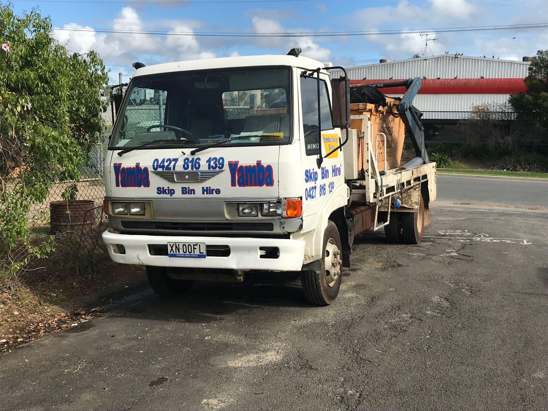 Happy Man Standing Beside A Skip Bin Truck — Gardners Yamba Skip Bin Hire In South Grafton, NSW