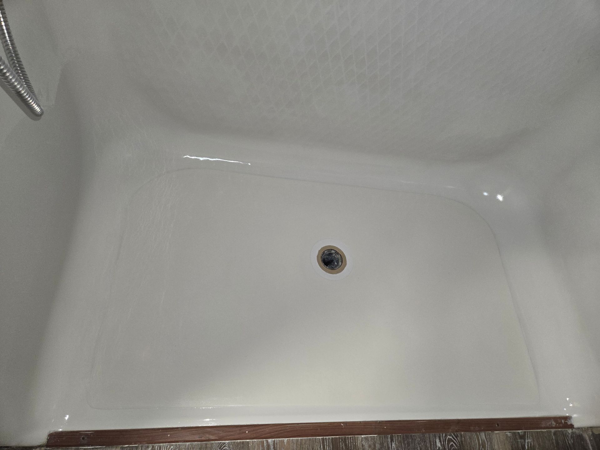 White painted wall with a small hole and a damaged spot near a metal screw or fixture below.