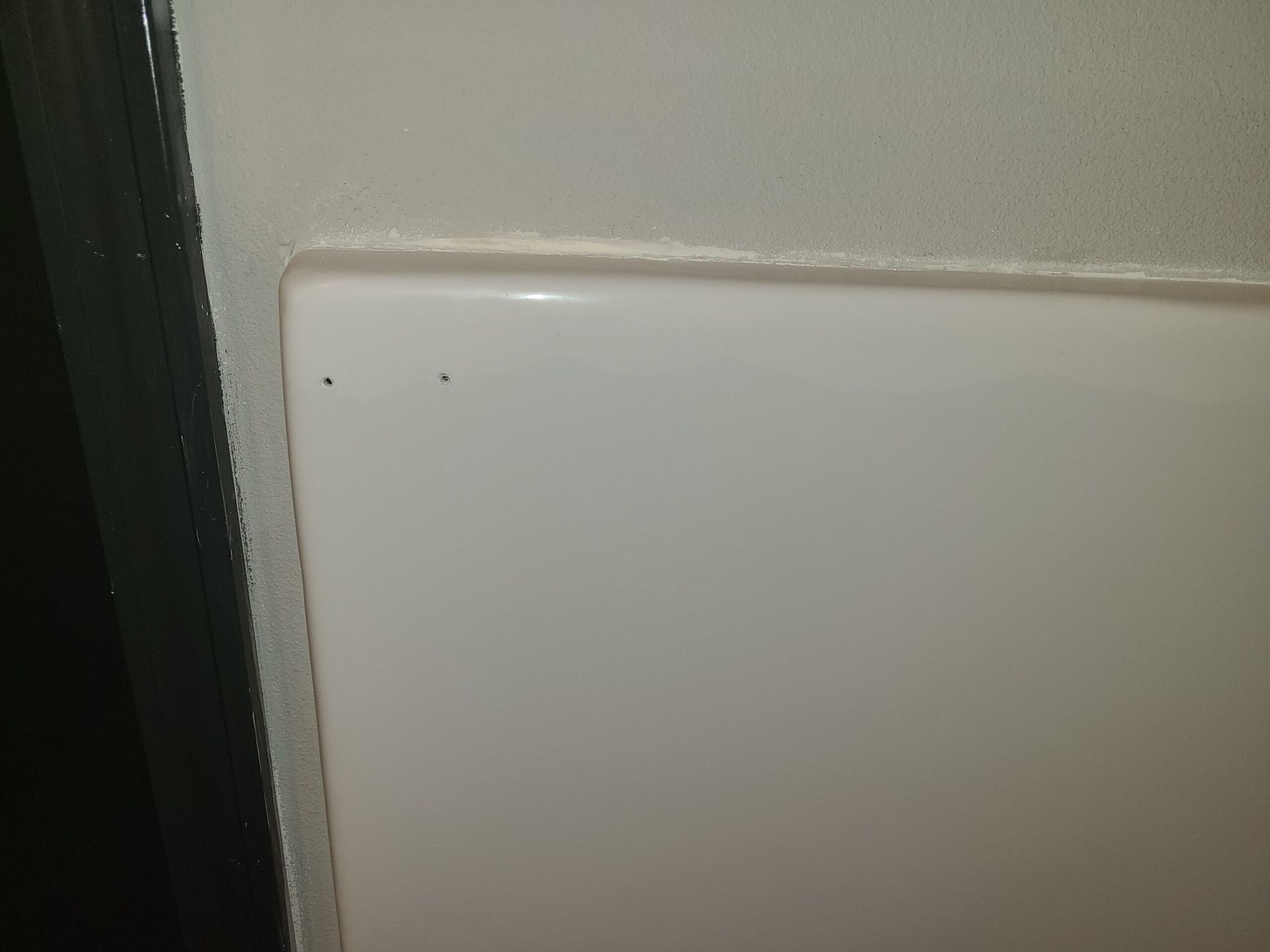 White light switch plate on a beige wall near a dark door frame