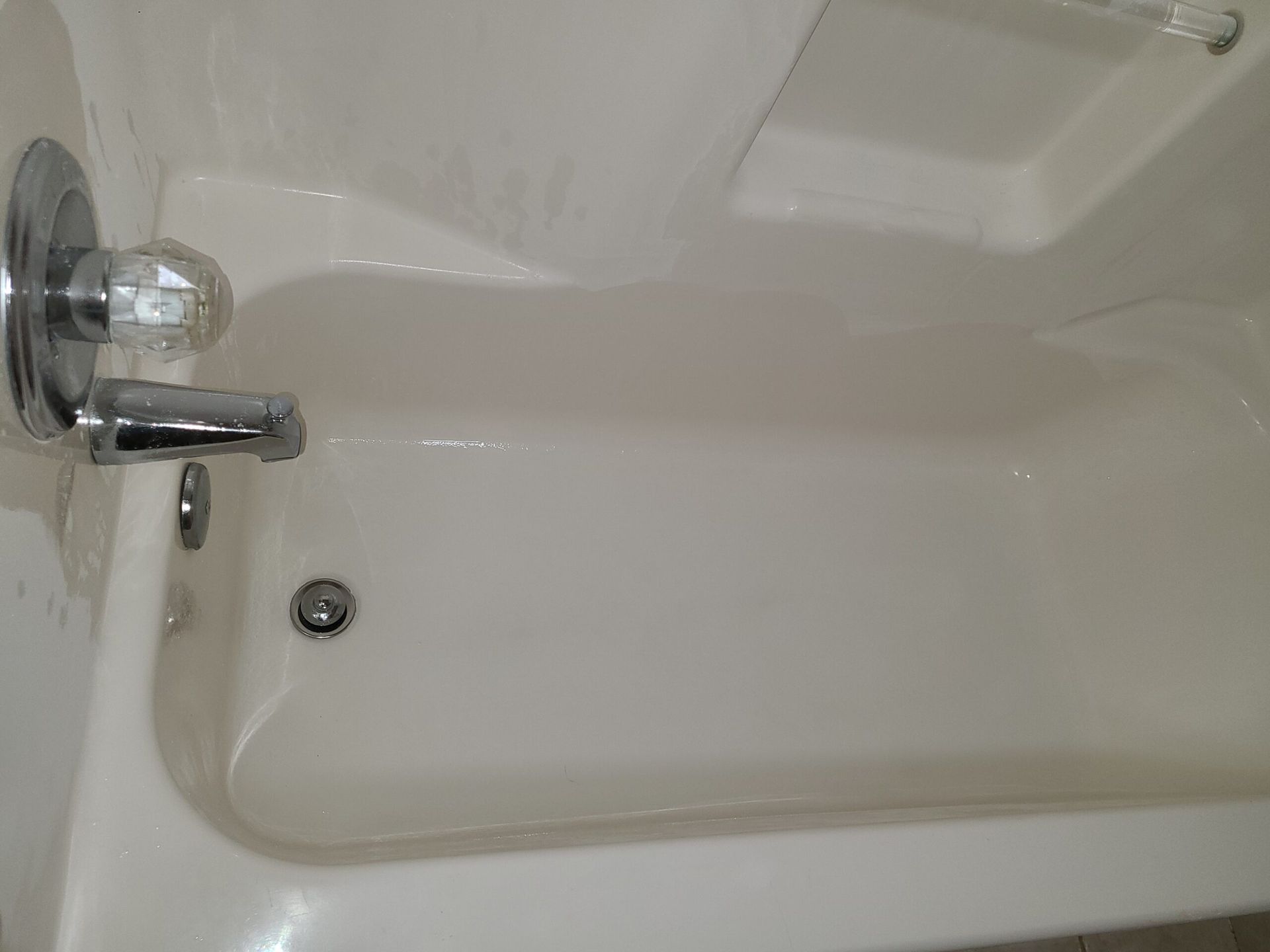 Empty white bathtub with chrome faucet and drain stopper