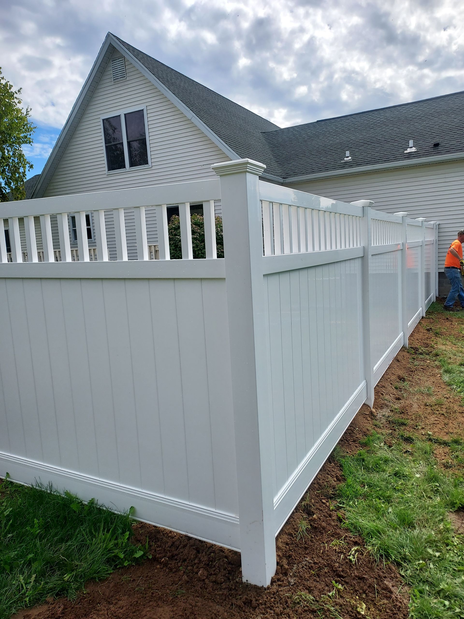 A white fence is surrounded by trees and a stone wall