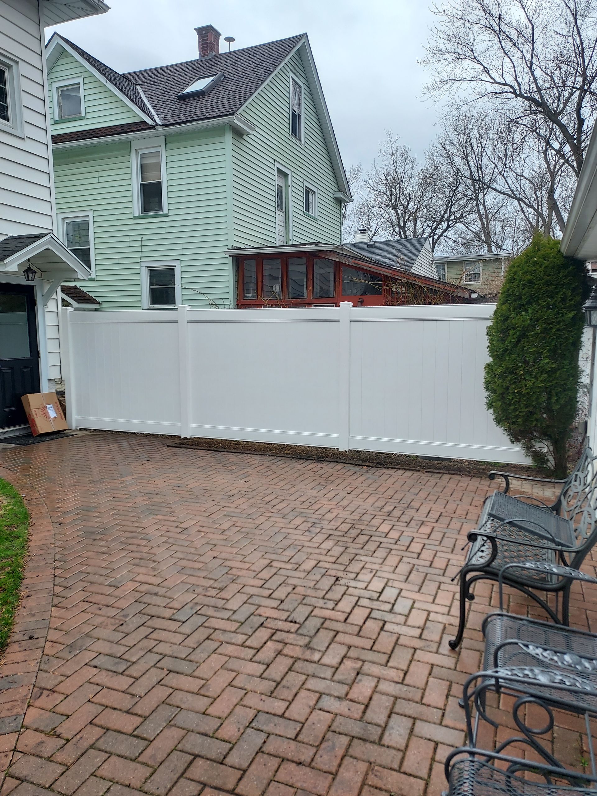 A white fence with a gate is sitting on top of a lush green field.
