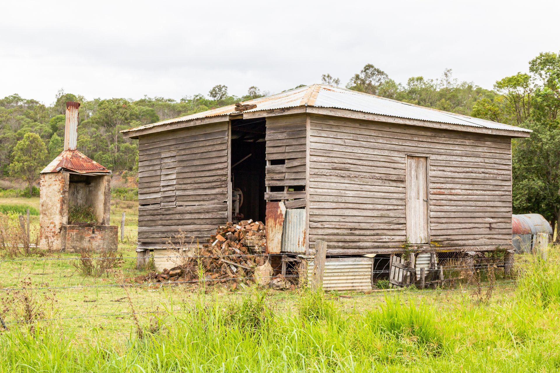 An old wooden house is sitting in the middle of a grassy field.