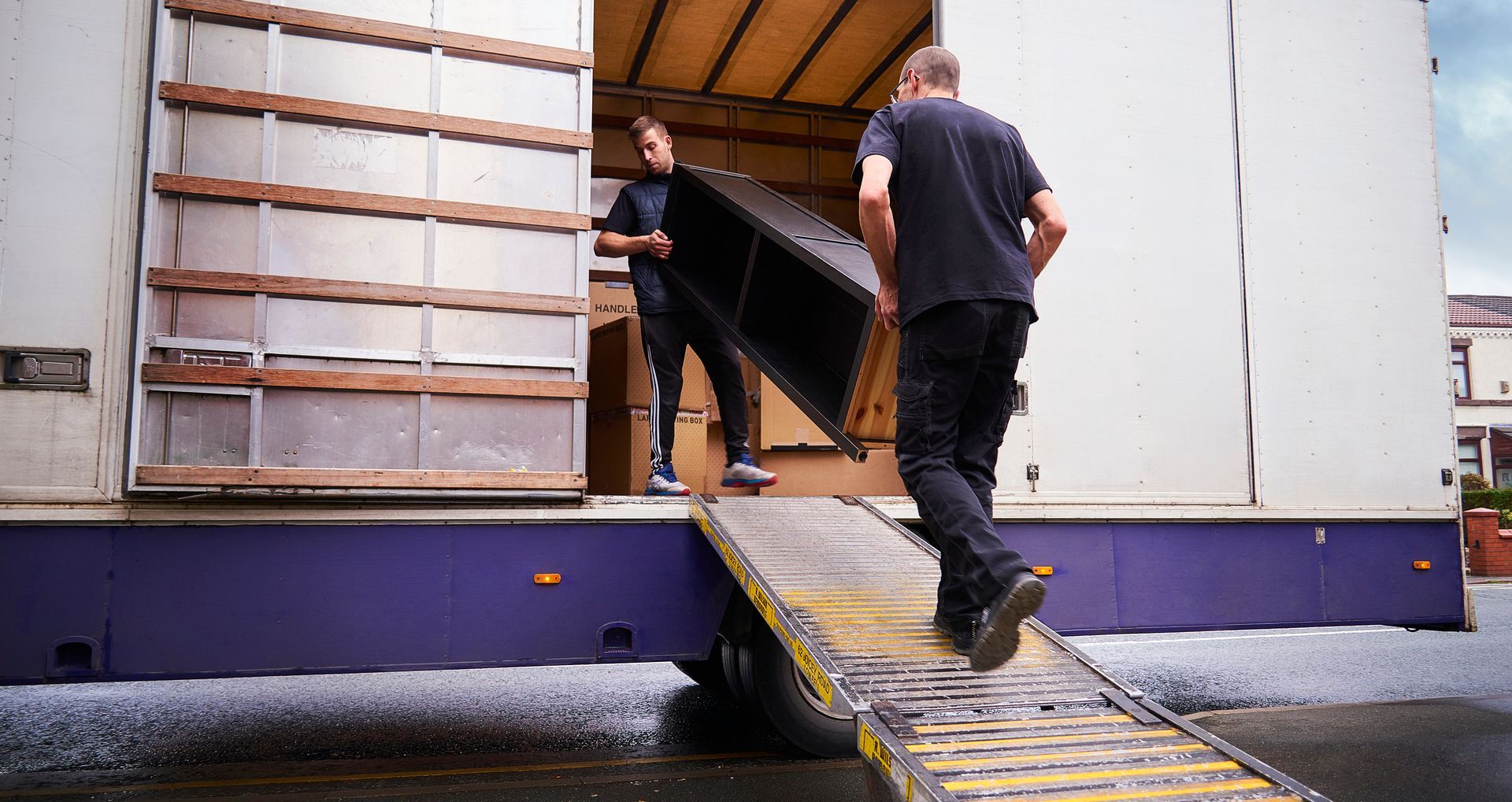 Two men are loading a large item into a truck.