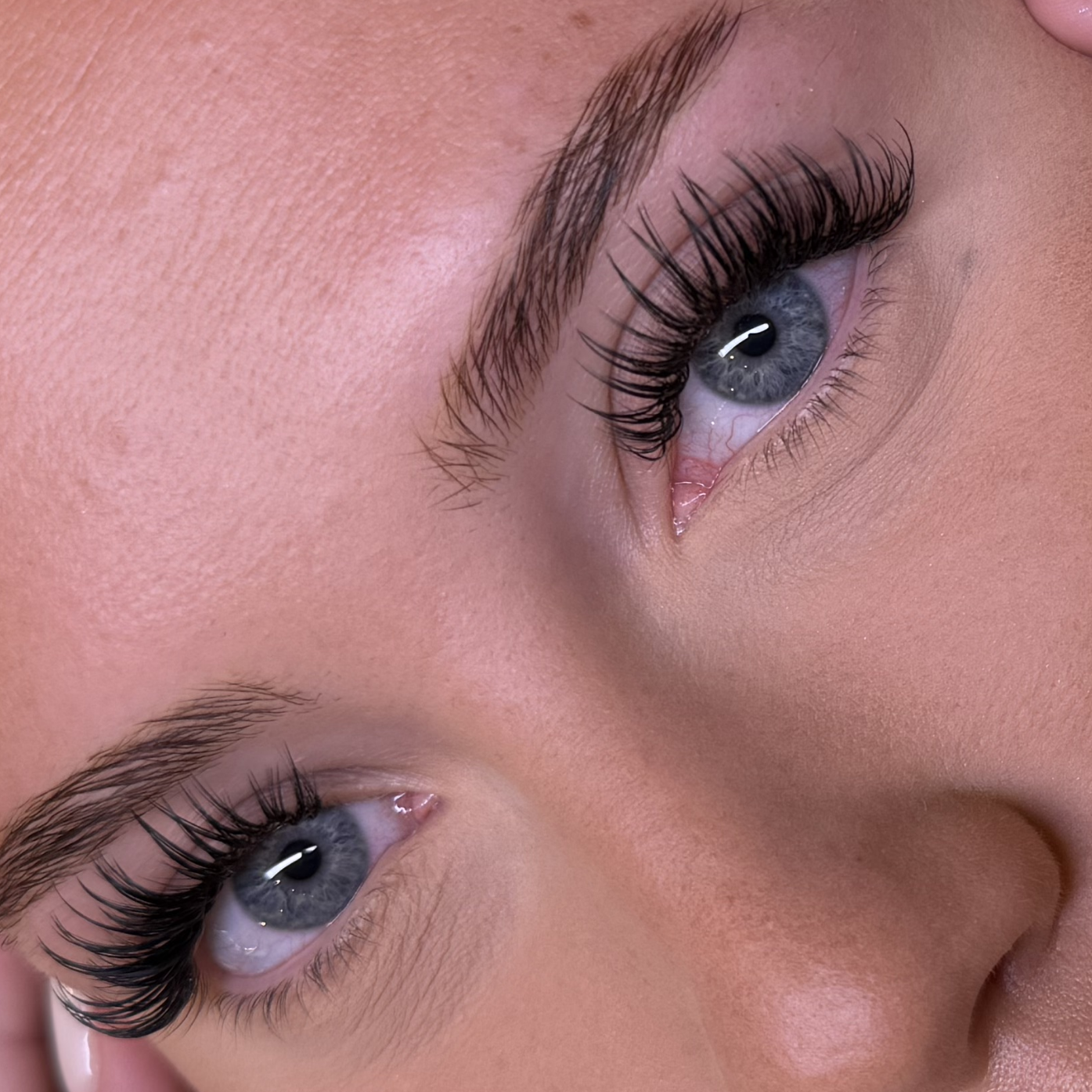 Eine Nahaufnahme des Gesichts einer Frau mit langen Wimpern und blauen Augen.