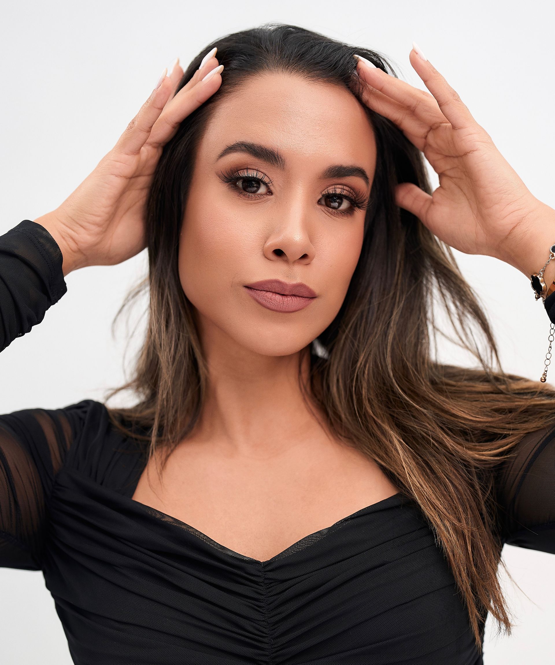A woman in a black top is holding her hair in her hands