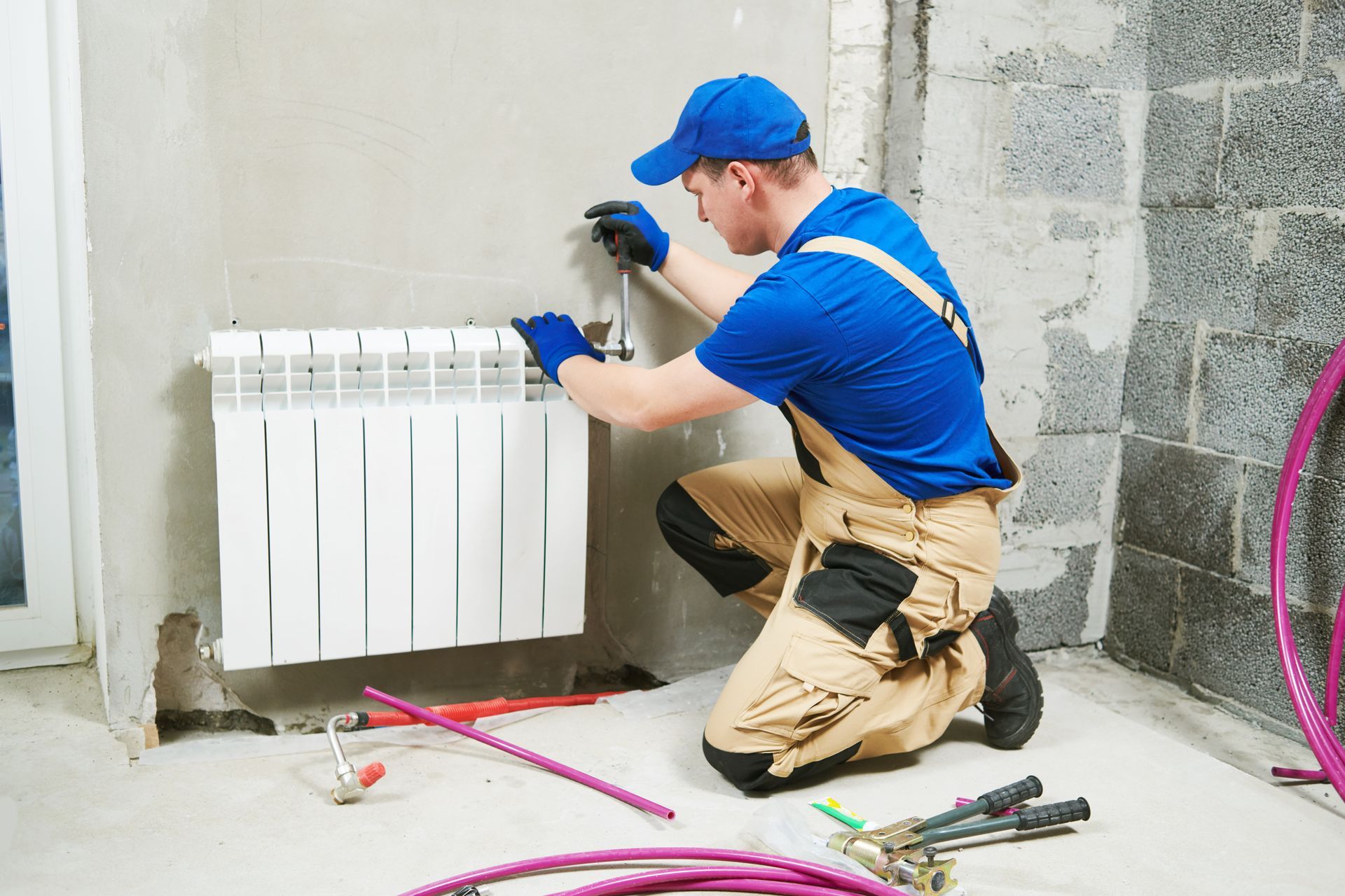 A man is installing a radiator on a wall.