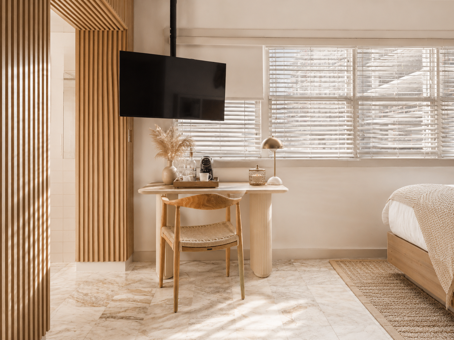 Cozy bedroom corner with desk, chair, wall-mounted TV, window blinds, and a bed in warm wood tones