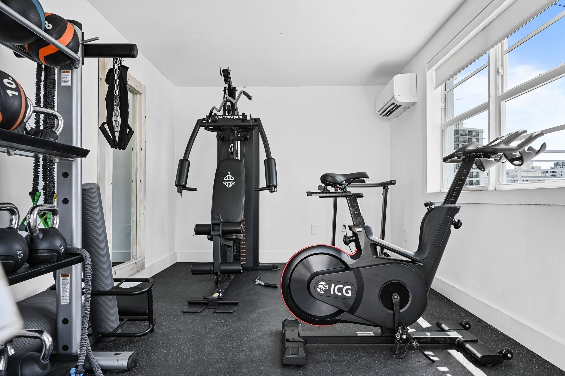 Home gym with exercise bike, weight machine, and kettlebells in a bright room