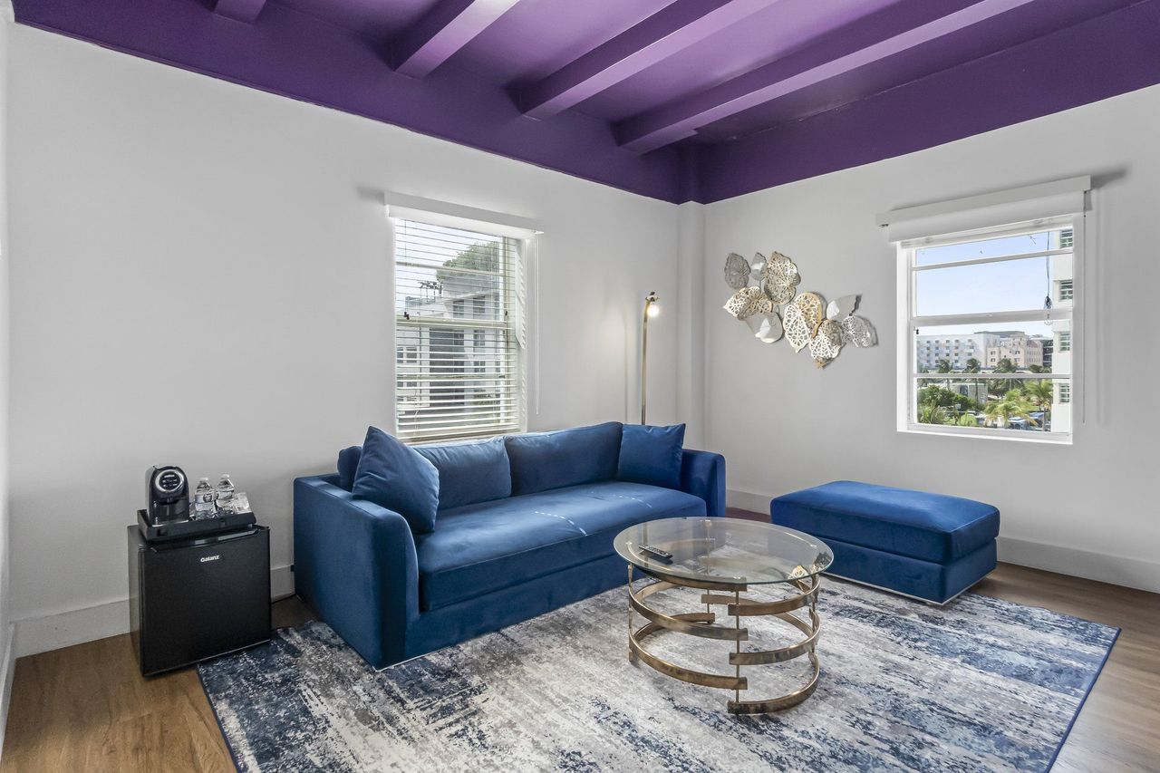 Suite living area with blue sofa and painted beamed ceiling