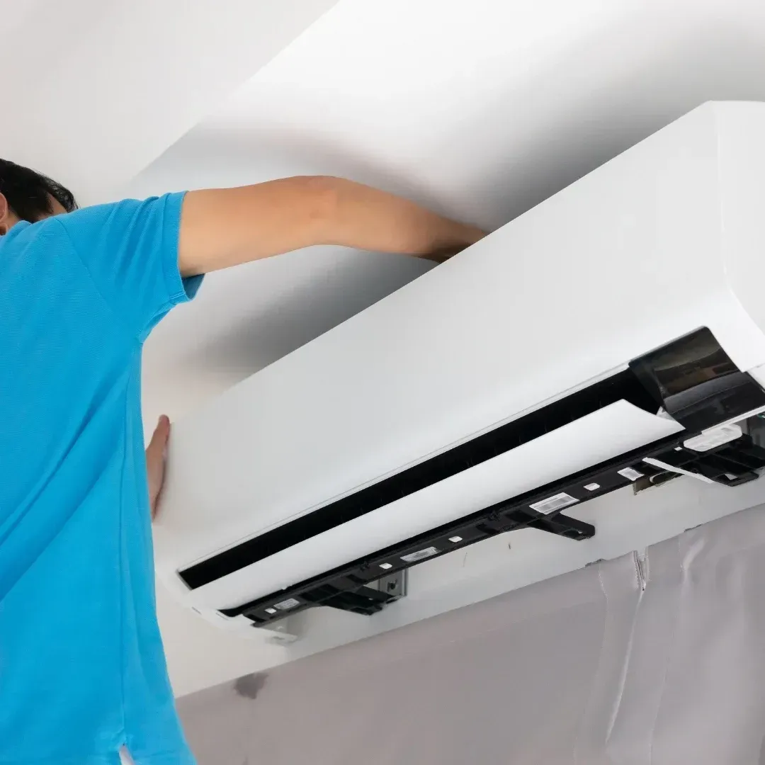 Person installing a white wall-mounted air conditioner with the front panel open