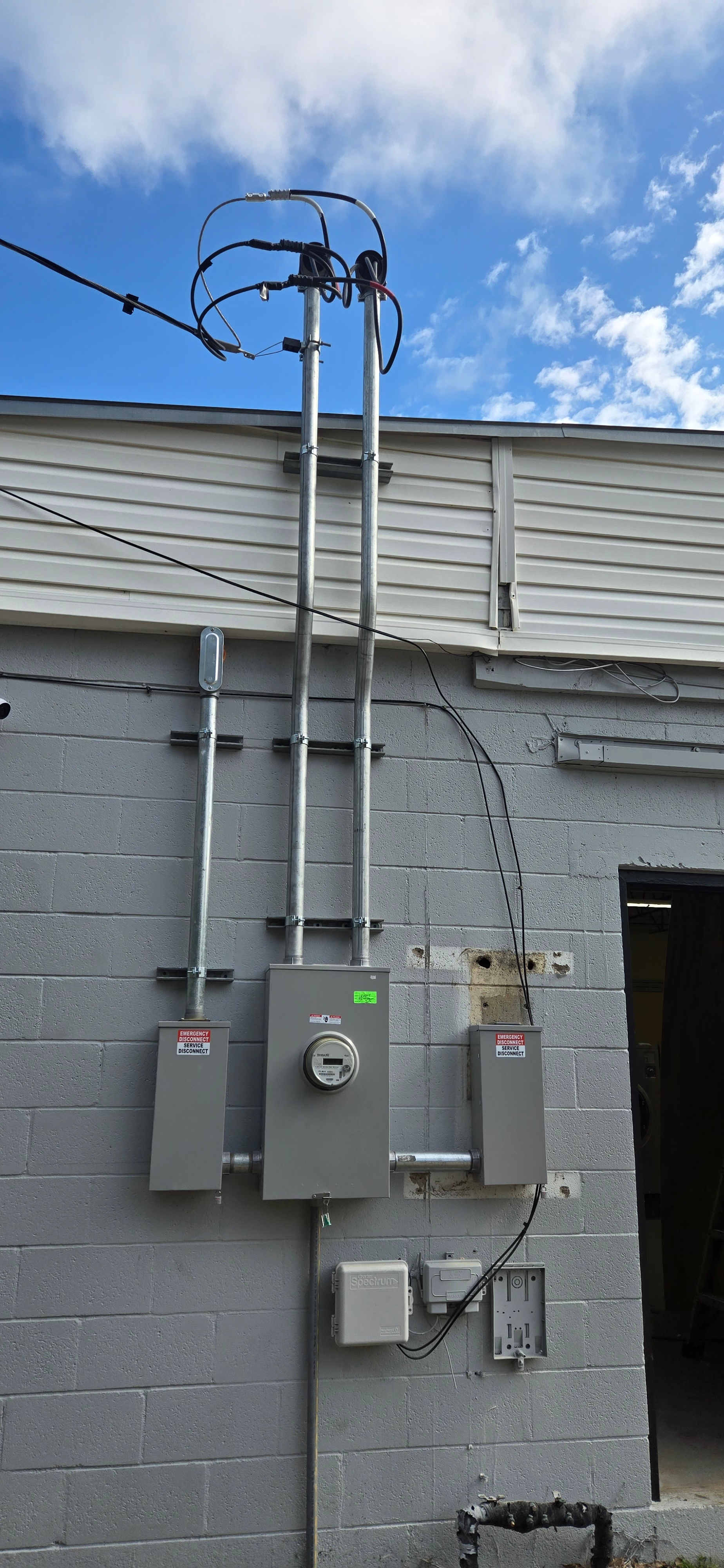 Outdoor electrical meter and utility boxes mounted on a gray brick building with overhead power lines