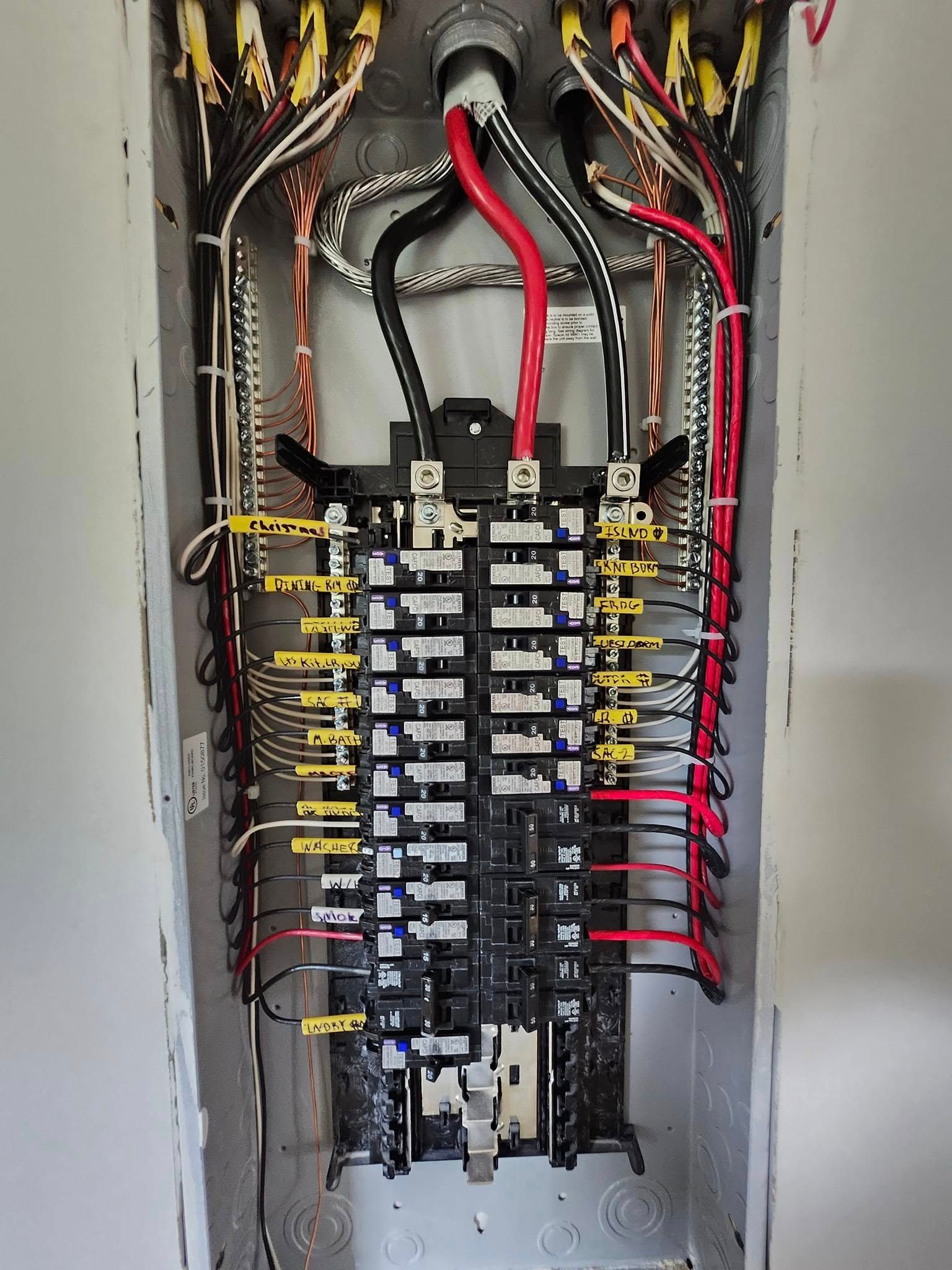 An open electrical panel with color-coded wiring connected to multiple circuit breakers.