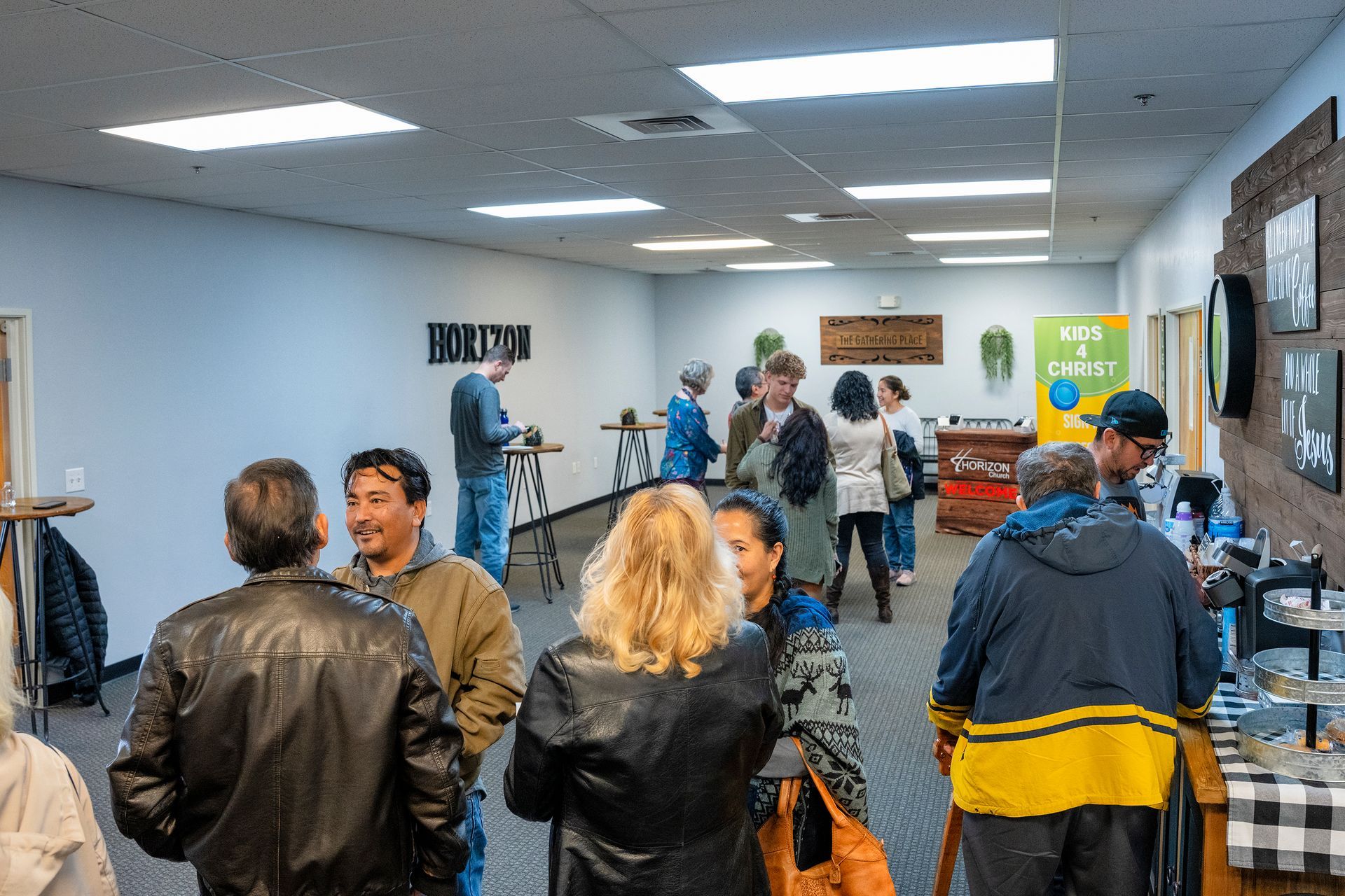A group of people are standing in a room talking to each other.