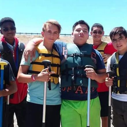 A group of young men are posing for a picture while wearing life jackets