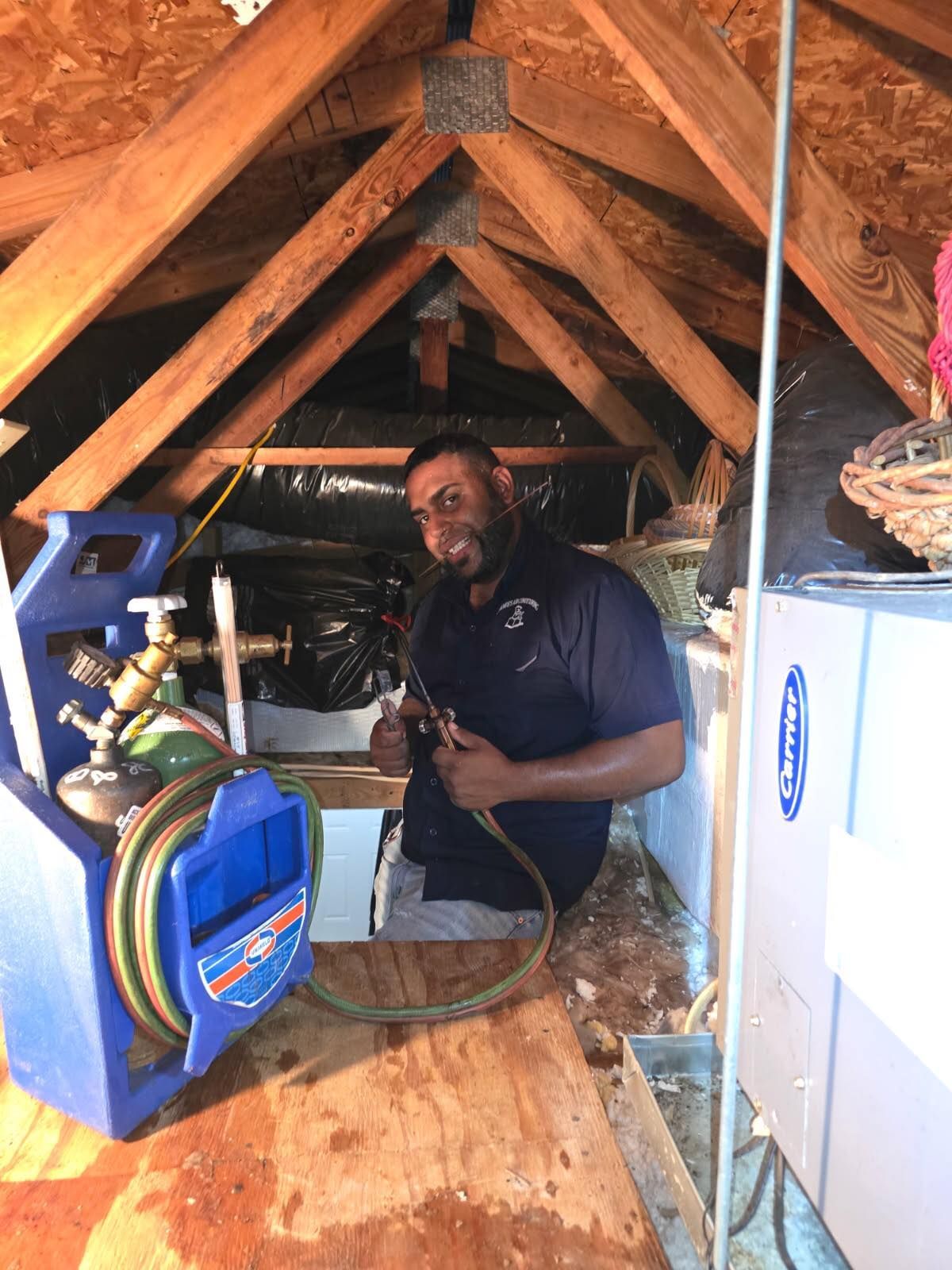 Man repairing an HVAC unit inside a hallway closet with the access panel open.