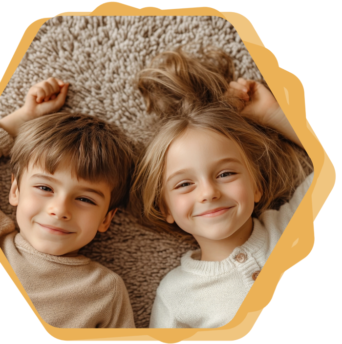 Two smiling children lying on a beige carpet, framed by a yellow wavy border
