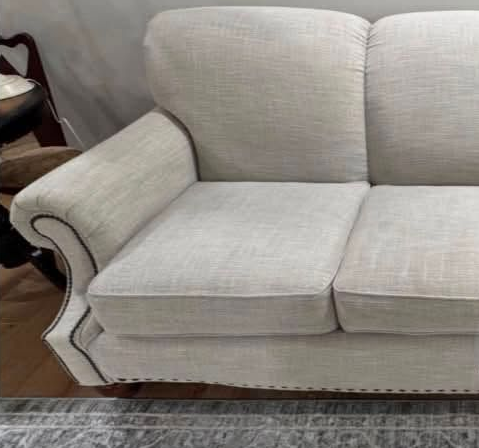 Light beige upholstered sofa with rolled arm and two seat cushions on a rug