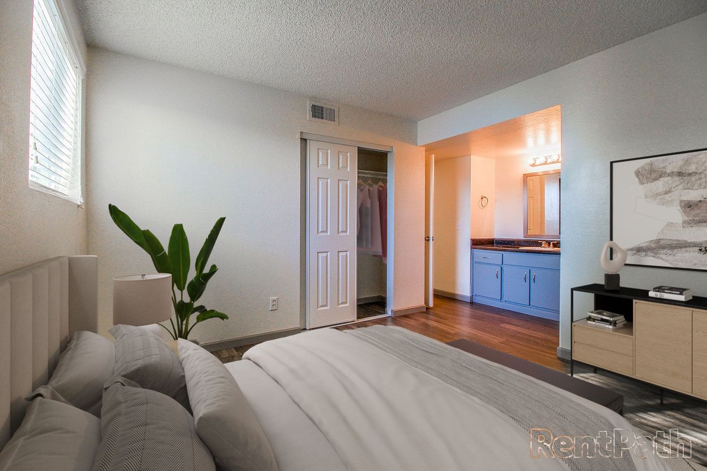 Bedroom with bed, closet, and doorway to a bathroom with blue cabinets.