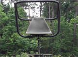 A chair is sitting in the middle of a forest.