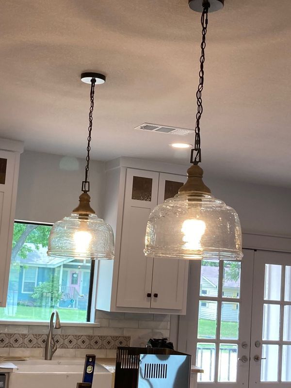 A kitchen with two clear glass pendant lights hanging from the ceiling