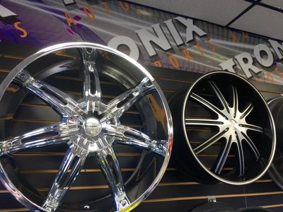 Shiny chrome and black alloy car rims on display in an auto shop.