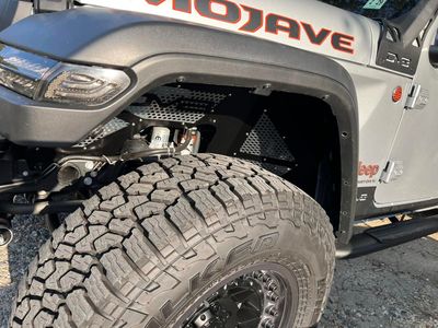 Close-up of a gray Jeep Gladiator Mojave's front wheel, showcasing the tire and fender detail.