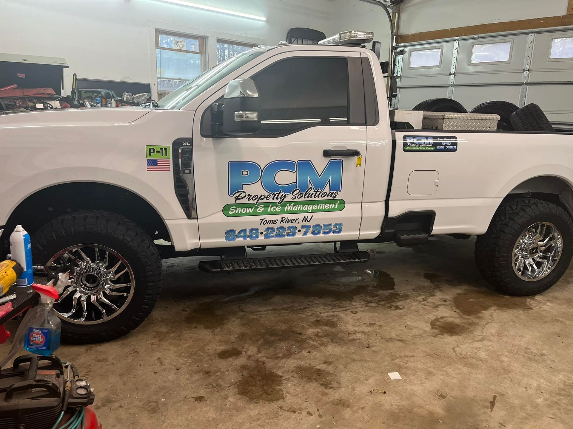 White pickup truck with PCM logo, in a garage.