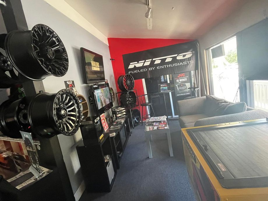 Interior of a tire shop with display wheels, black and red accents, and a waiting area.