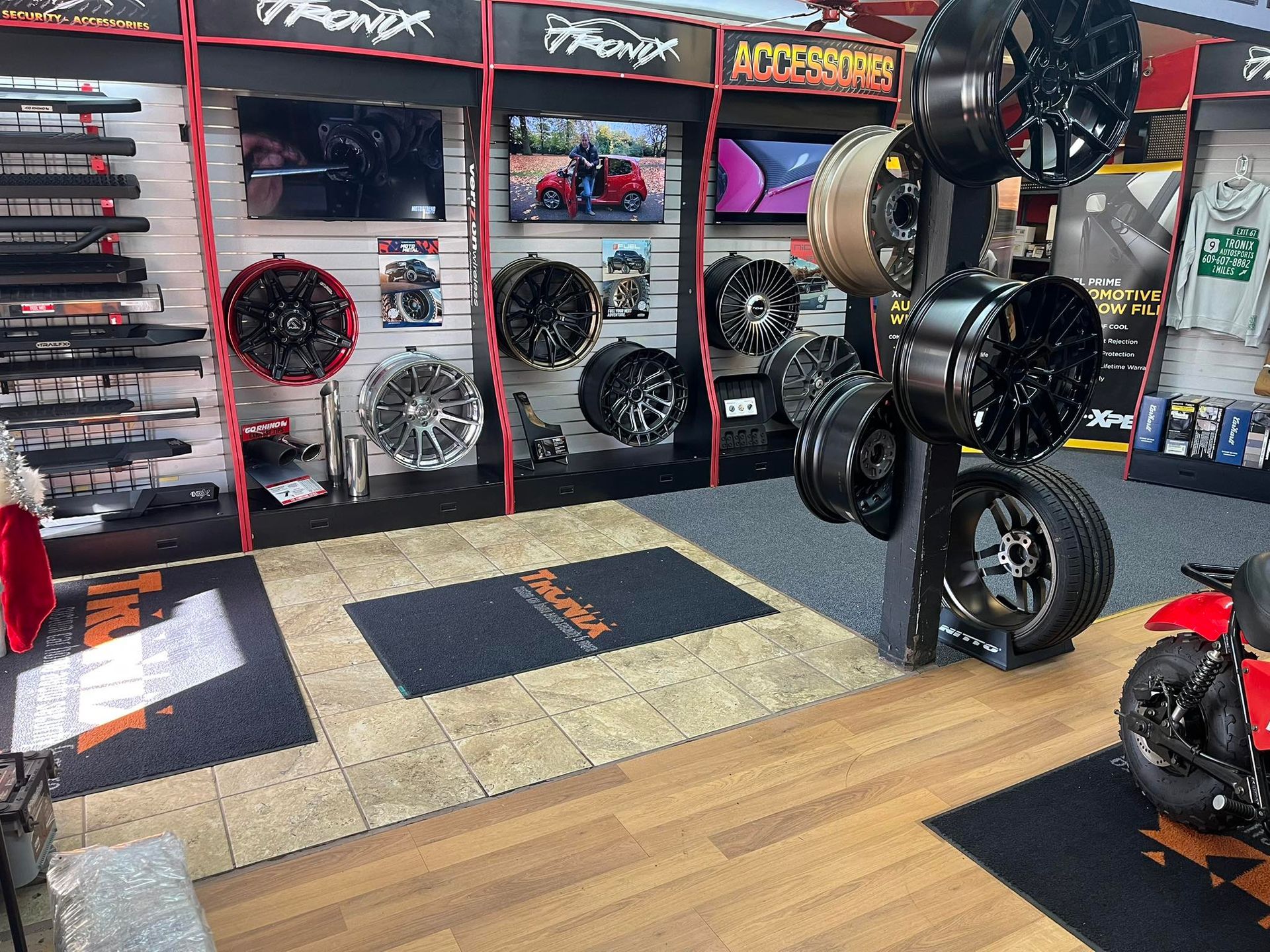 Inside auto parts store, display of wheels and accessories; black, red, and silver.