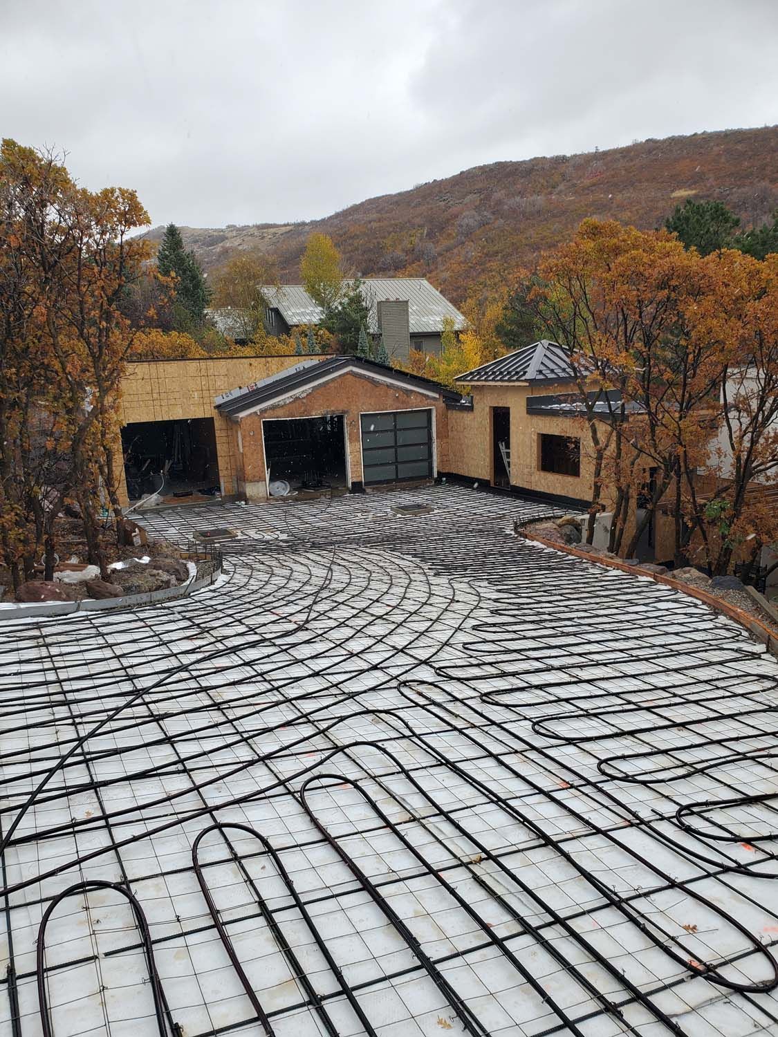 Driveway with radiant heating system, garage, and autumn landscape.
