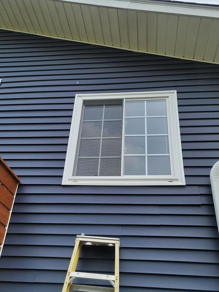 A ladder is sitting on the side of a house next to a window.