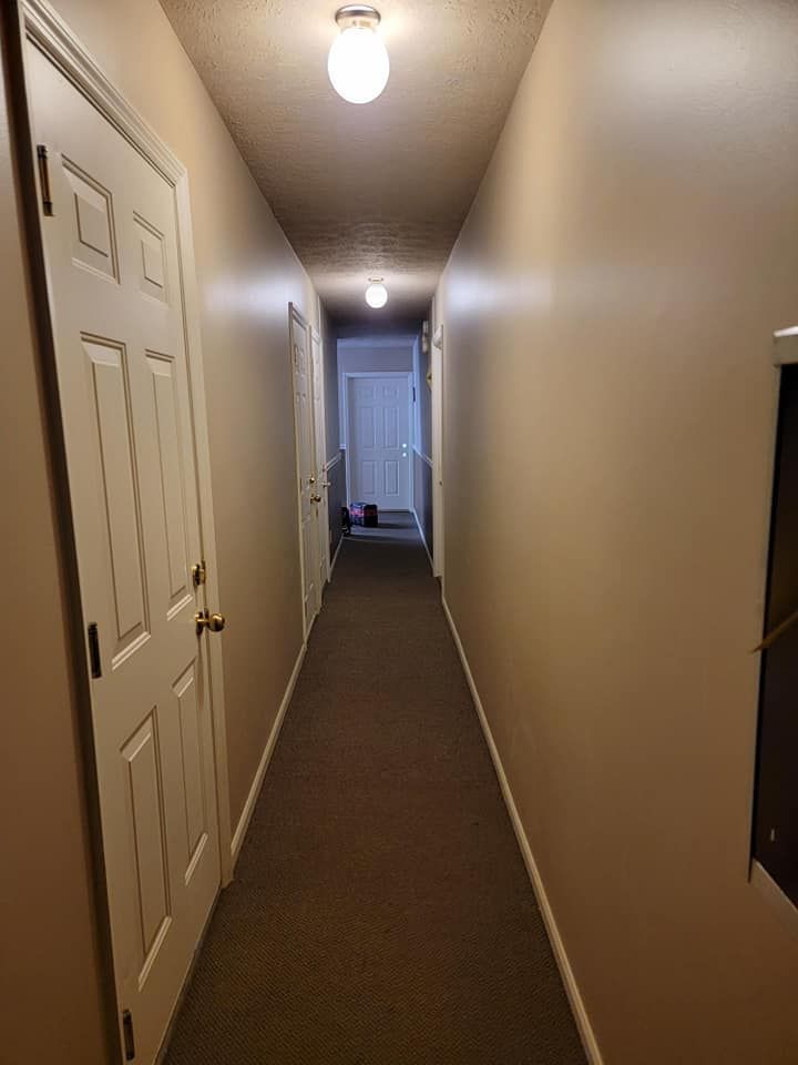 A long hallway with a lot of doors and a light on the ceiling.