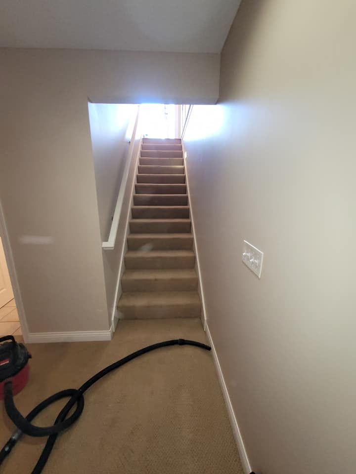 A vacuum cleaner is sitting in a hallway next to stairs