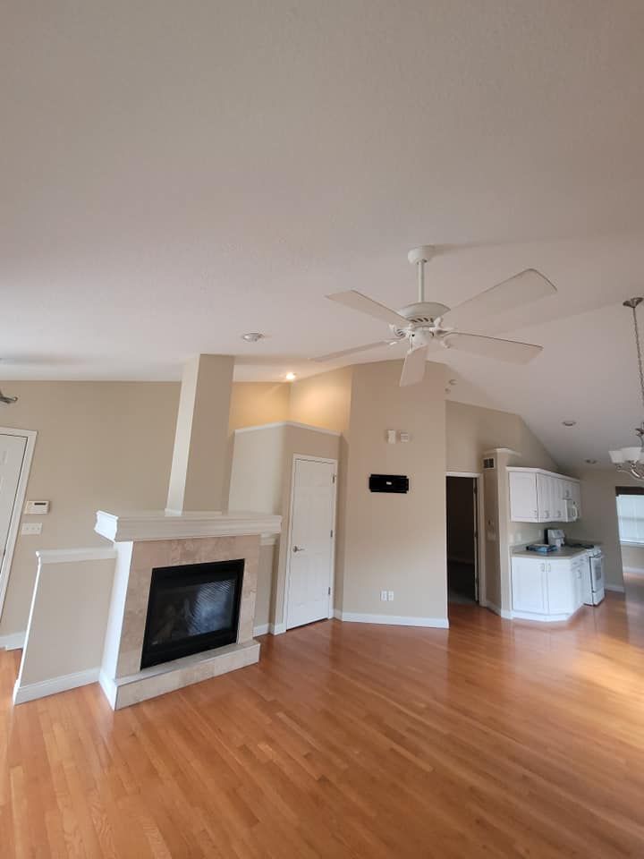 A living room with hardwood floors , a fireplace and a ceiling fan.