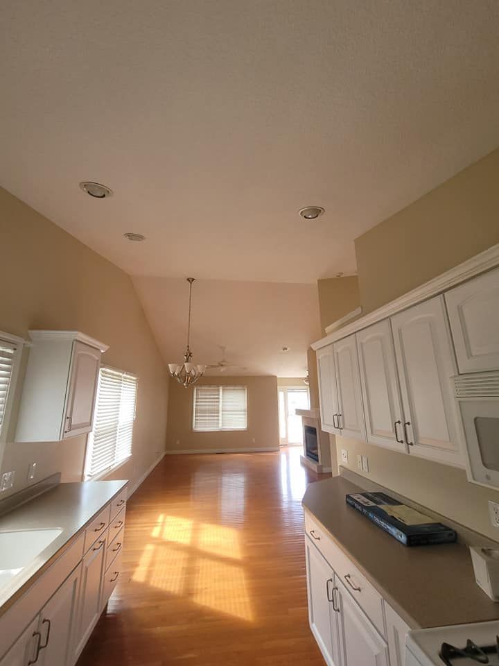 A kitchen with white cabinets and hardwood floors in a house.