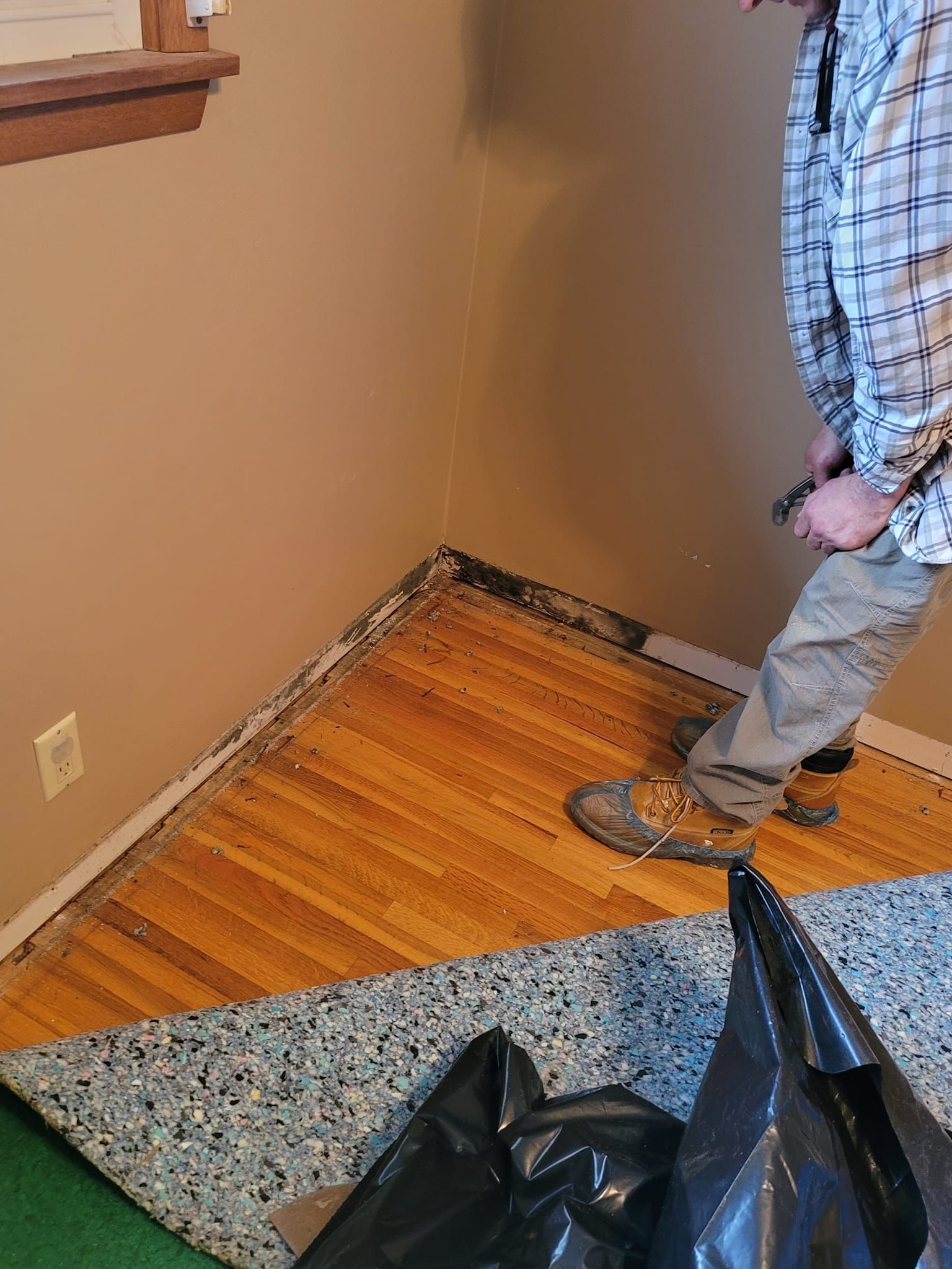 A man is standing on a wooden floor in a room.