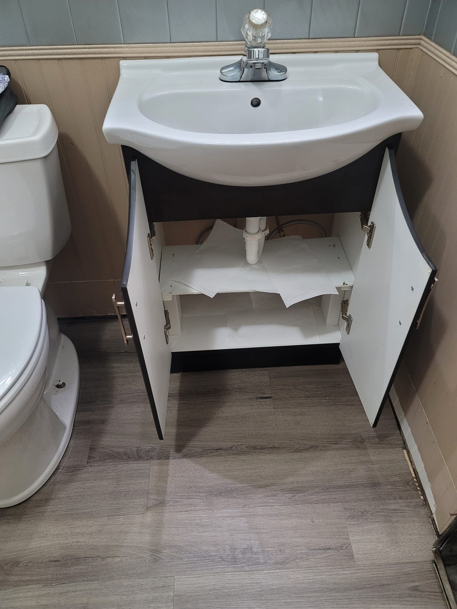 A bathroom with a sink and toilet with the cabinet open.