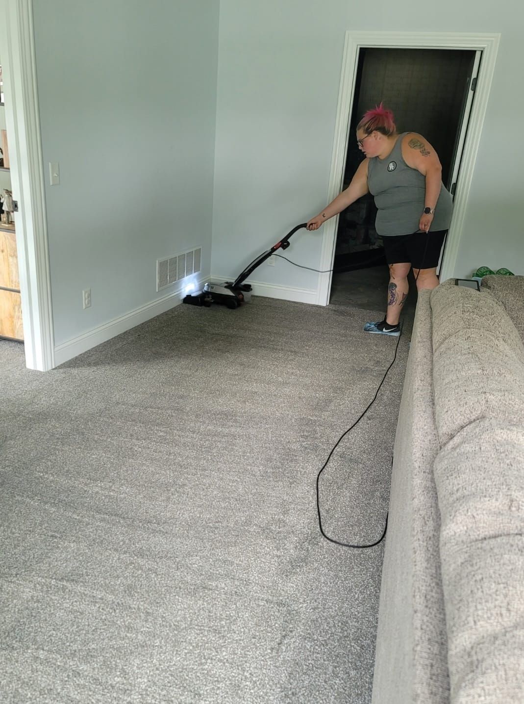 A woman is vacuuming the carpet in a living room.