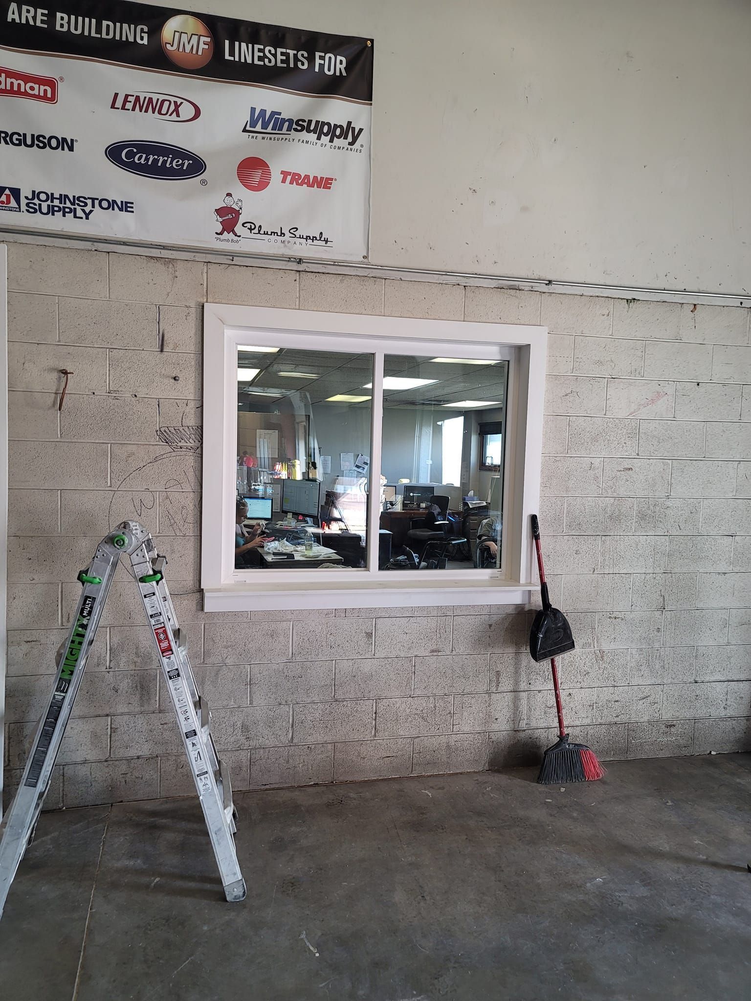 A ladder sits in front of a window with a sign above it that says ame building