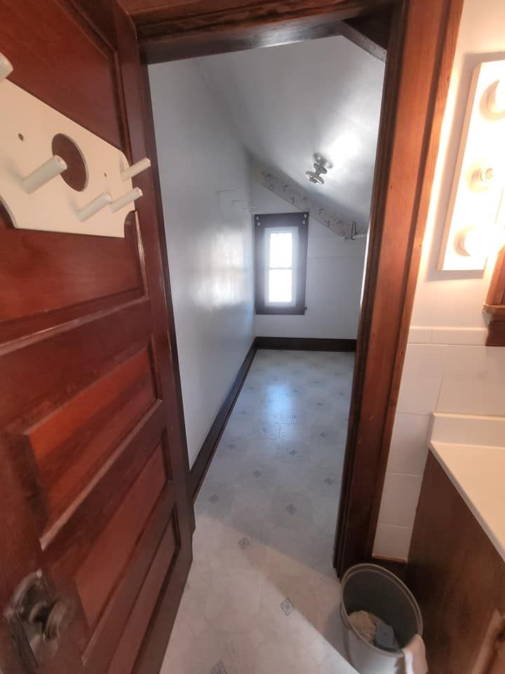A bathroom with a wooden door and a bucket on the floor