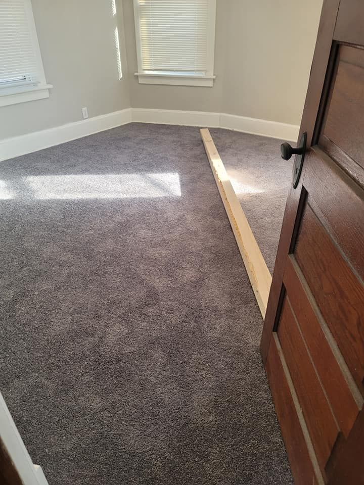 A room with a gray carpet and a wooden door.